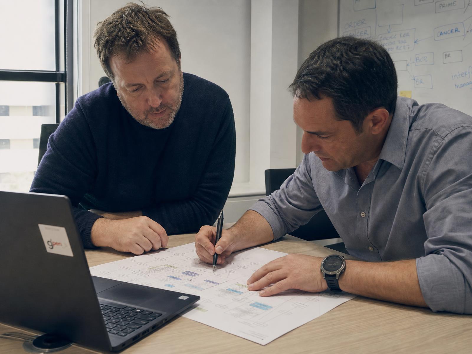 Two Vector Dominion engineers annotating a printed data model diagram